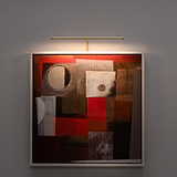 A framed abstract painting in brown, red, and beige tones is lit by a Harrow 580mm antique brass light.