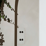 4G Vertical Two Way Toggle Switch in Paintable Bronze on a wall with leafy shadows, compatible with 4G Switches & Dimmers.