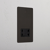 Bronze shaver socket with black insert on grey wall. 