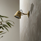 Cambridge Wall Floodlight in antique brass finish mounted outdoors, angled light highlights textured beige wall.