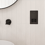 Bronze and black shaver socket fixed to white wooden slatted bathroom wall next to bronze tap and bronze framed mirror