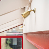 Antique Brass Bayliss Single 50mm Spotlight fitted  to a white wall on the right with red metal beam beneath. 
