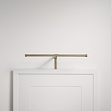 A Harrow Picture Light 400mm in antique brass is mounted above a white-framed picture on a white wall.