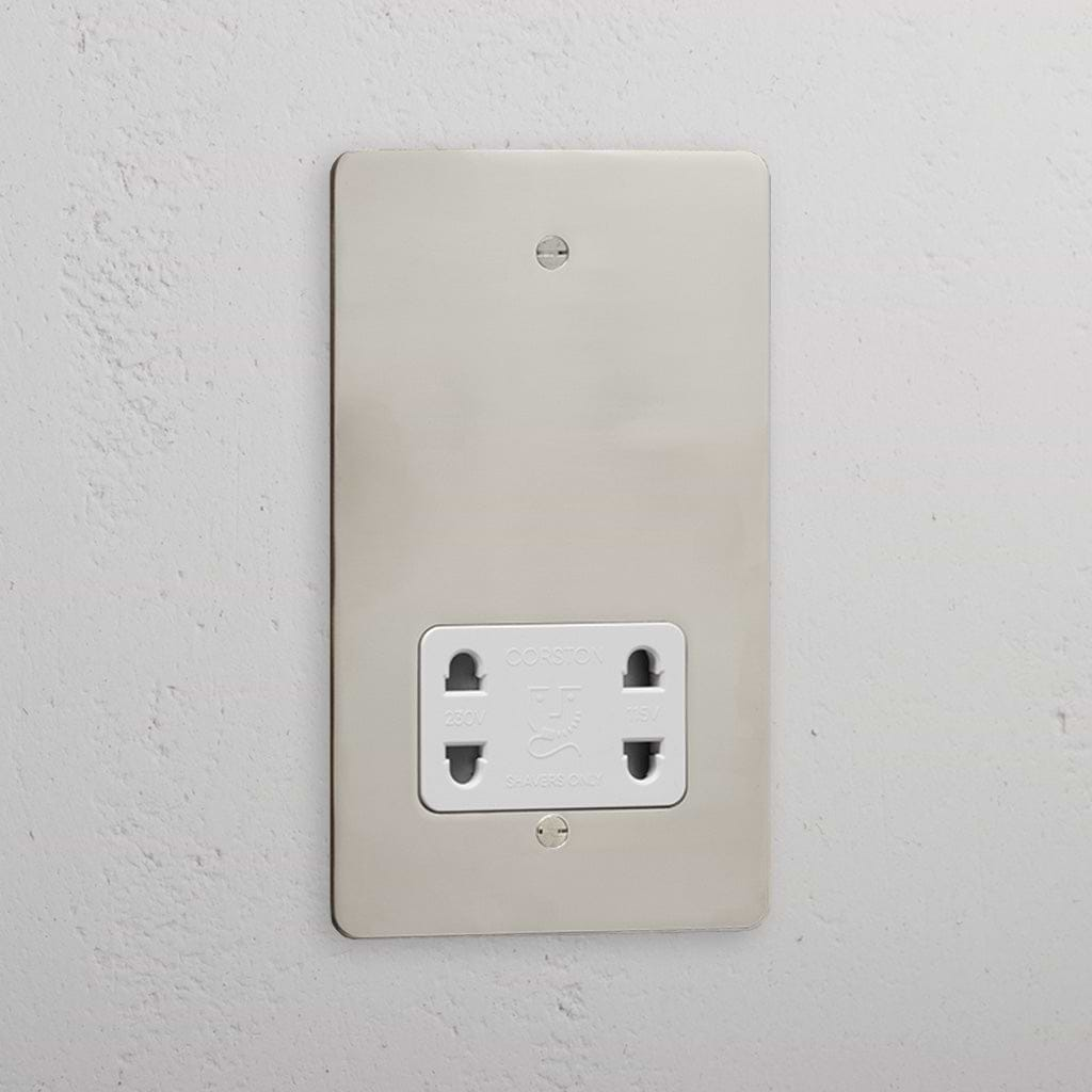 Polished nickel shaver socket with white insert on grey wall. 