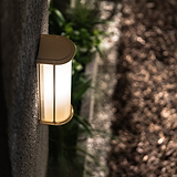 Medium wall light featuring antique brass finish and fluted glass shade, mounted on a gray wall.