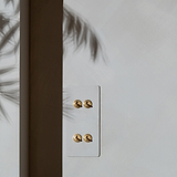 4G Vertical Two Way Toggle Switch in paintable antique brass, showing elegant design with leaf shadows on the wall.