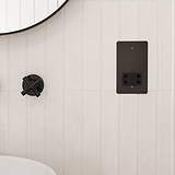 Bronze and black shaver socket fixed to white wooden slatted bathroom wall next to bronze tap and bronze framed mirror