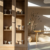Bronzener Bayswater-Möbelknauf auf einem Holzschrank, dessen elegantes Design durch das Sonnenlicht hervorgehoben wird.