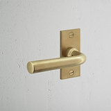 Apsley gefederter Türgriff kurzes Schild in antikem Messing auf weißem Wand für klassische Eleganz.