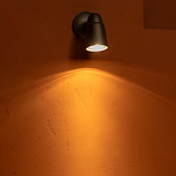 Ealing Außenwandstrahler – Bronze – Licht, das von einer Terrakotta-Steinwand nach unten strahlt.
