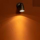 Brons Ealing Inbouwspot wandmodel dat licht naar beneden werpt op een terracotta stenen muur.