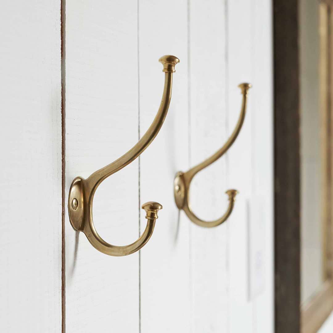Two Antique Brass Mews Coat Hooks on A Wall