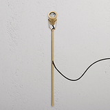 Cambridge Grond Spotlight Ã¢â‚¬â€œ Antiek Messing, een buitenspot met zwarte kabel, tegen witte muur.
