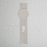 Onslow gefederter Türgriff langes Schild + Euro-Schloss in poliertem Nickel auf einer strukturierten weißen Wand.