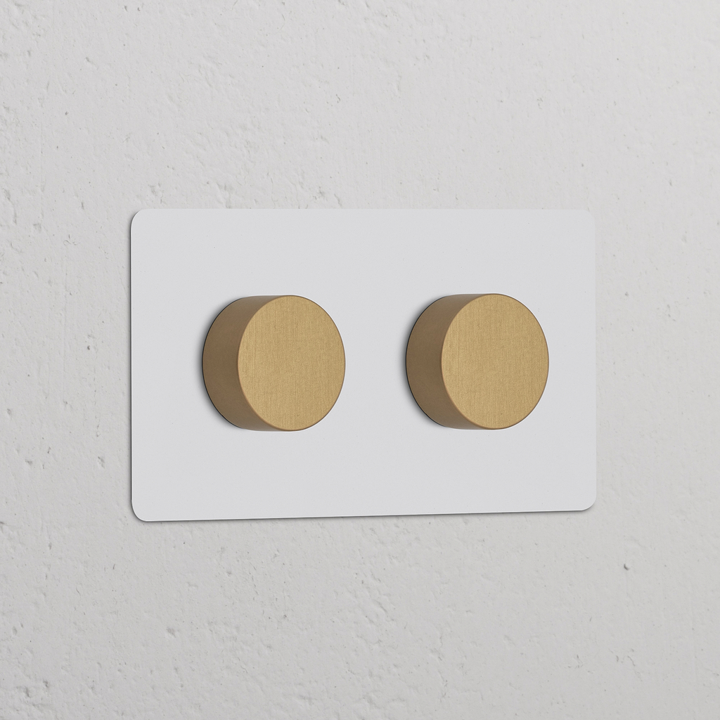 Zweifachrahmen mit 2x Dimmerknopf – Lackierbar + Antikes Messing an weißer Wand montiert.