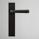 Bronze Digby gefederter Türgriff langes Schild auf strukturierter weißer Wand, eleganter langer Plattentürgriff.