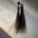 Portland Haken – Bronze, ein eleganter Wandhaken aus Bronze, mit dezenter Beleuchtung an einer strukturierten Wand montiert.