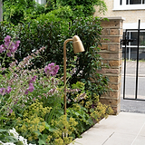 Ealing Wegestrahler – Outdoorbeleuchtung in antikem Messing, beleuchteter Gartenweg neben Ziegelpfeiler.