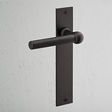 Harper Fixer Türgriff langes Schild in Bronze-Finish mit langer rechteckiger Rückplatte vor einer hellgrauen Wand.