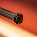 Taylor Bilderleuchte 220 mm in Bronze, eine elegante Bilderleuchte vor einem kontrastierenden orangefarbenen Hintergrund.