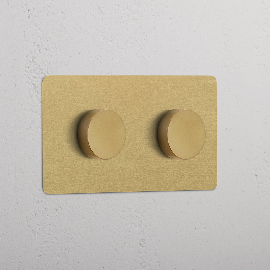 Zweifachrahmen mit 2x Mehrpunkt-Dimmerschalter in antikem Messing mit runden Drehknöpfen, ein weißer Wand.