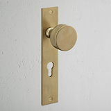 Onslow gefederter Türgriff langes Schild + Euro-Schloss in antikem Messing auf weißer Wand montiert.
