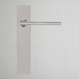 Clayton gefederter Türgriff langes Schild in poliertem Nickel auf einer strukturierten weißen Wand.