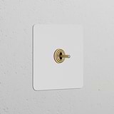 Lichtschalter mit zentriertem Kippschalter in einem lackierbaren, schlichten Rahmen, Finish in antikem Messing, für Schalter- und Dimmer-Einrichtung.