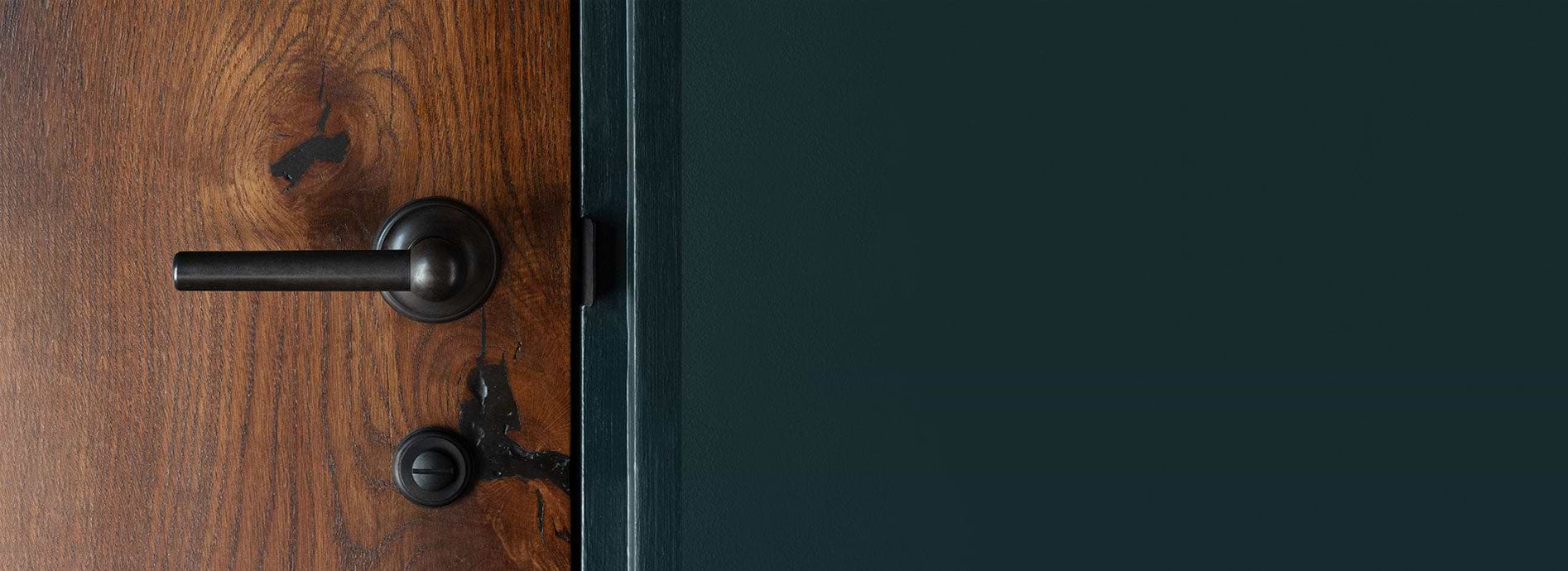 Bronze door handle by Corston on wooden door