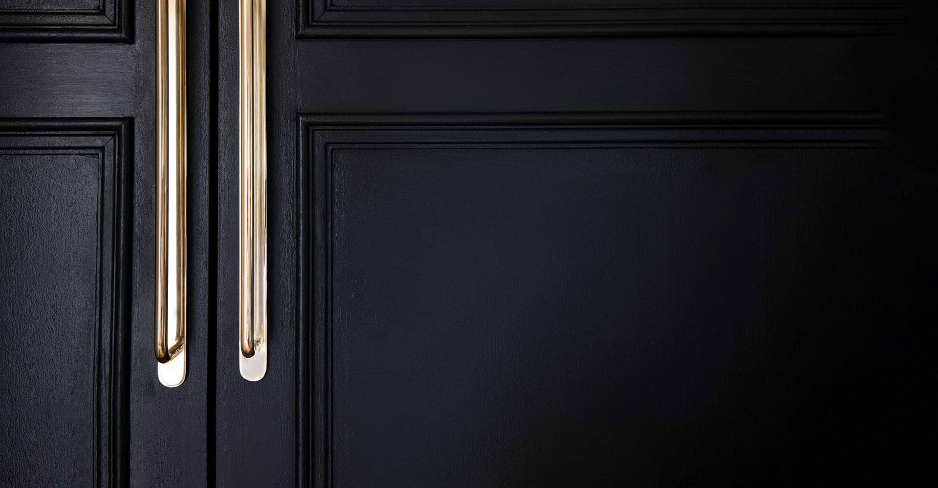 two antique brass poplar mortice door knobs on black doors