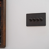 Bronze 4G two-way toggle switch panel with four switches, suitable for lighting control on a white wall.