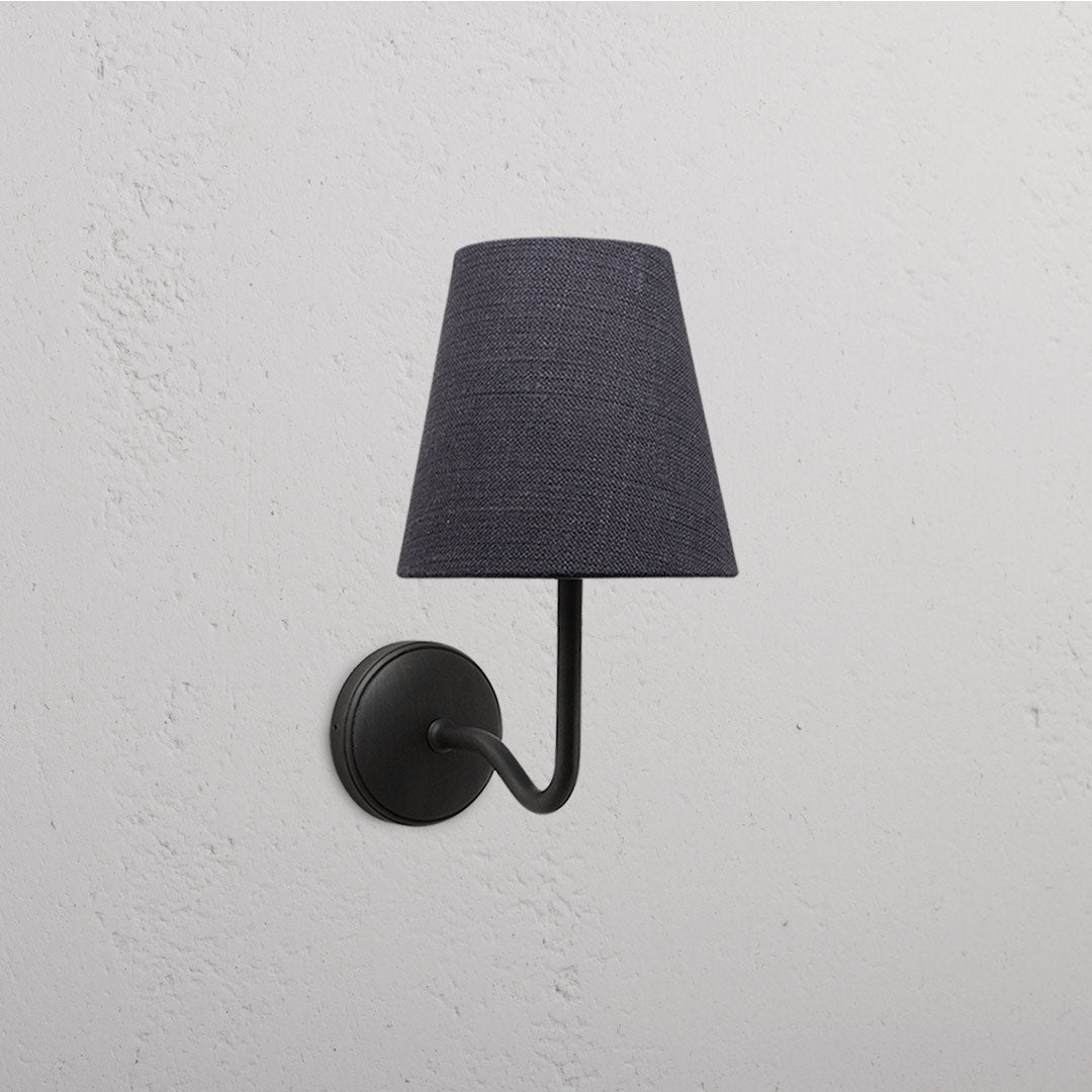 Malvern Medium Wall Light in Basalt Grey with Bronze accents, featuring a conical shade on a textured white wall.