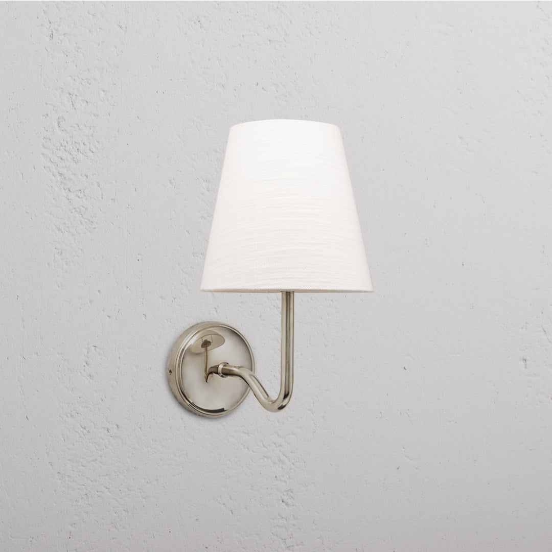 Malvern Medium Wall Light in Alabaster White with polished nickel finish and white conical shade on a textured wall.