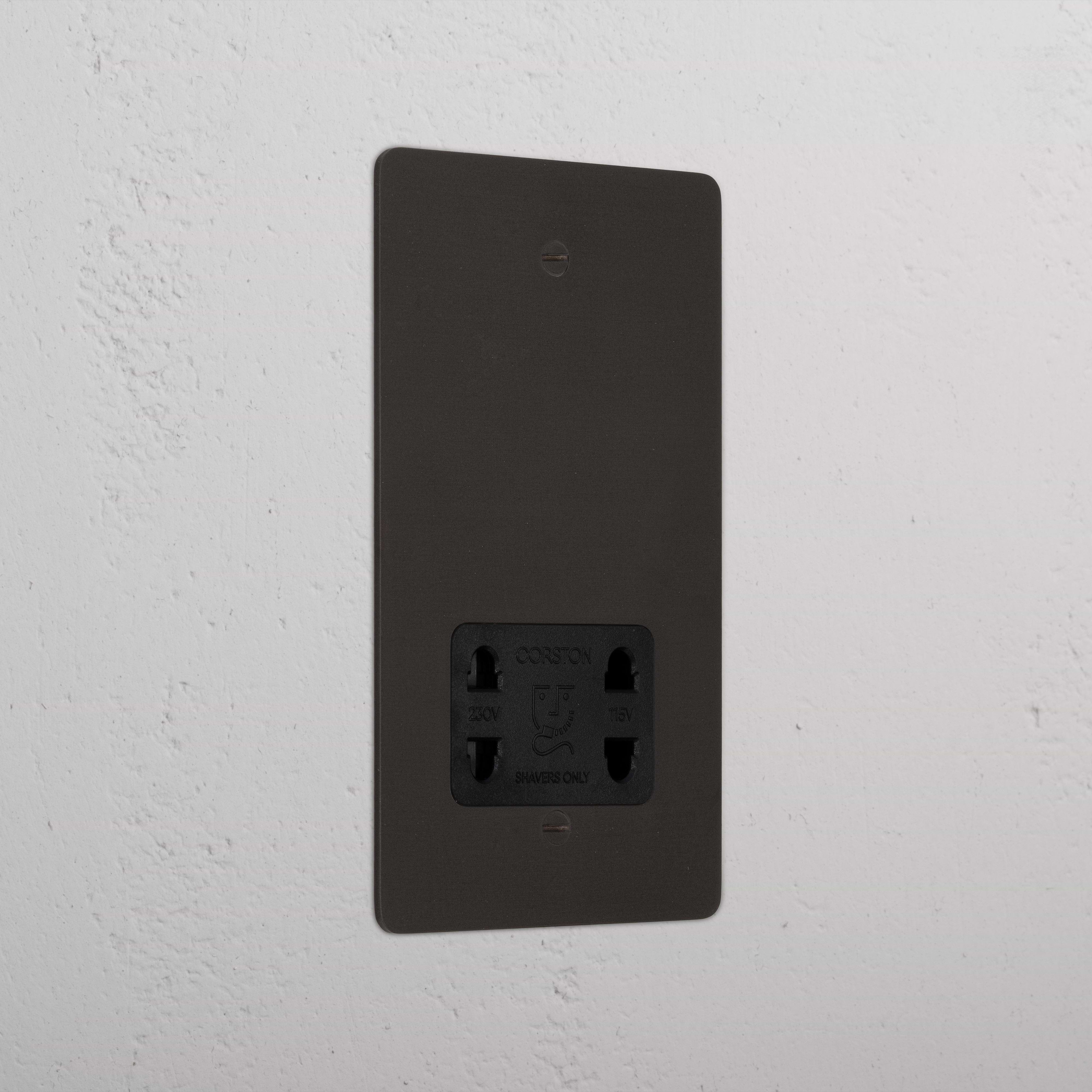 Bronze shaver socket with black insert on grey wall. 