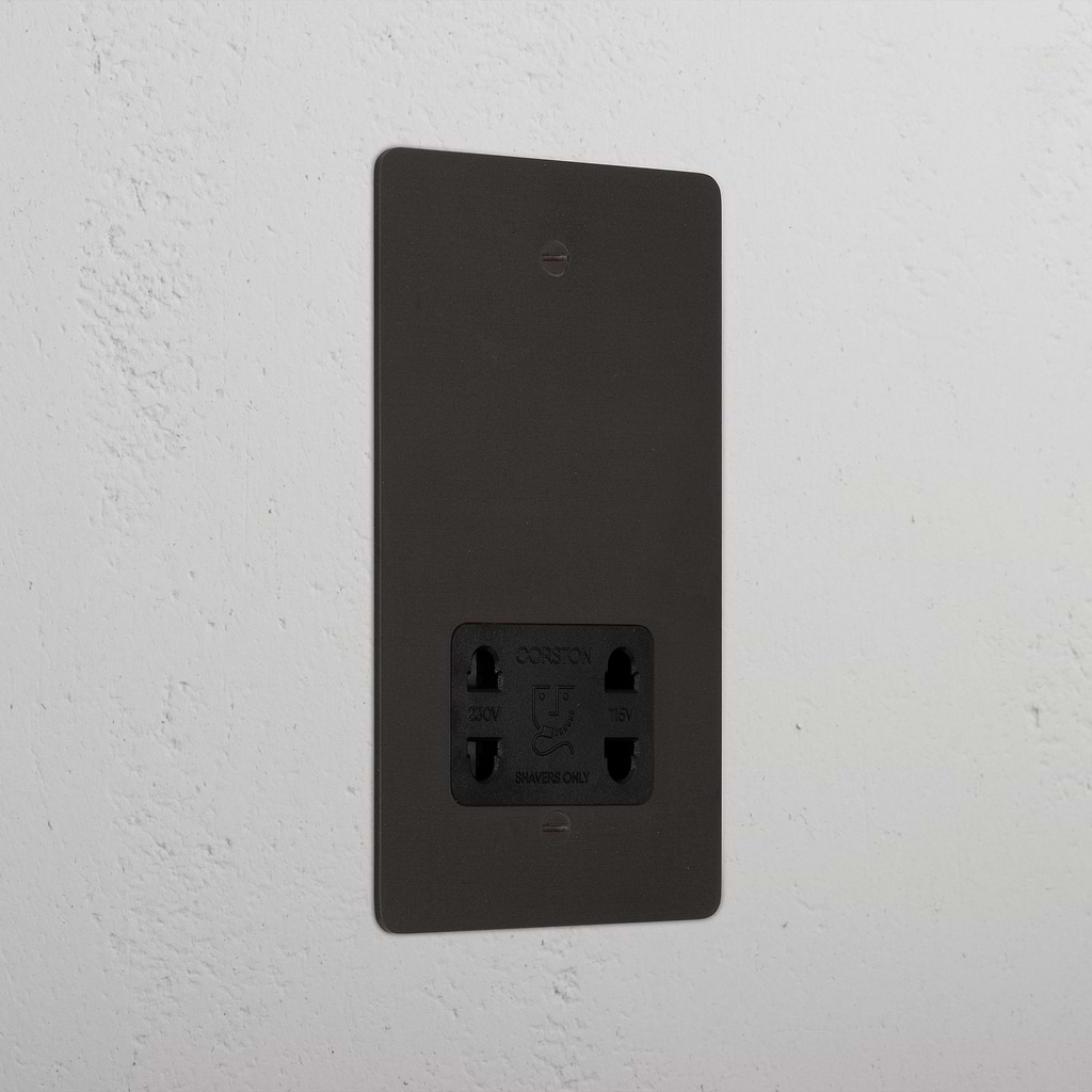Bronze shaver socket with black insert on grey wall. 