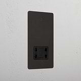 Bronze shaver socket with black insert on grey wall. 