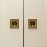 Close-up of a cabinet with two antique brass Regent Recessed Small Pull handles on neutral doors.