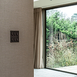 Bronze Black 6G Two Way Rocker Switch for elegant and efficient light control on a textured wall.