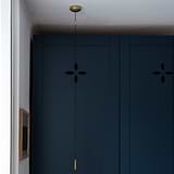 Antique brass bathroom pull isolator switch with dark pull cord against a dark blue paneled wall.