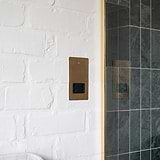 Shaver Socket - Antique Brass Black, 2G Sockets & Modules, on a white wall near a green tiled area.