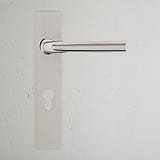 Polished Nickel Apsley Long Plate Sprung Door Handle & Euro Lock on a textured white wall with a matching keyhole.