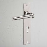 Polished nickel Harper Long Plate Sprung door handle with Euro lock keyhole, mounted on a white wall.