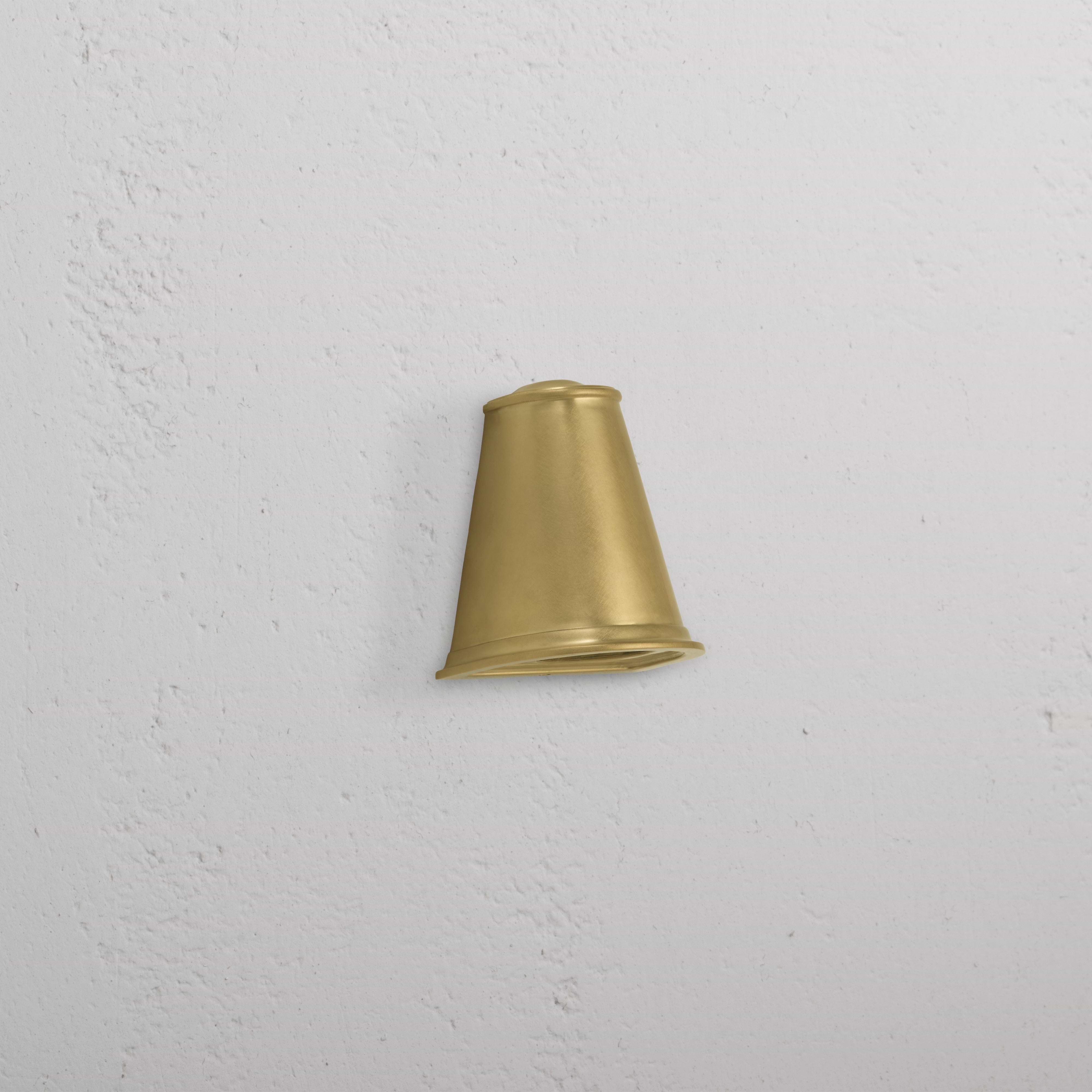 Southwark Mast Light – Antique Brass small wall light with a cone-shaped shade mounted on a white textured wall.