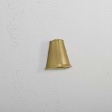 Southwark Mast Light – Antique Brass small wall light with a cone-shaped shade mounted on a white textured wall.