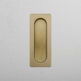 Antique Brass Regent Recessed Pull on a white textured wall.