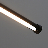 Close-up of a sleek, minimalist cylindrical LED light fixture in bronze, like the Harrow Picture Light.