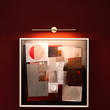 Abstract geometric painting on a red wall, illuminated by the Taylor Picture Light 580mm in Antique Brass.