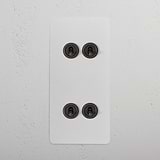 Four paintable bronze 4G vertical two-way toggle switches on a white wall panel.