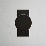 Bronze Onslow Short Plate Sprung Door Knob displayed on a textured white backdrop.