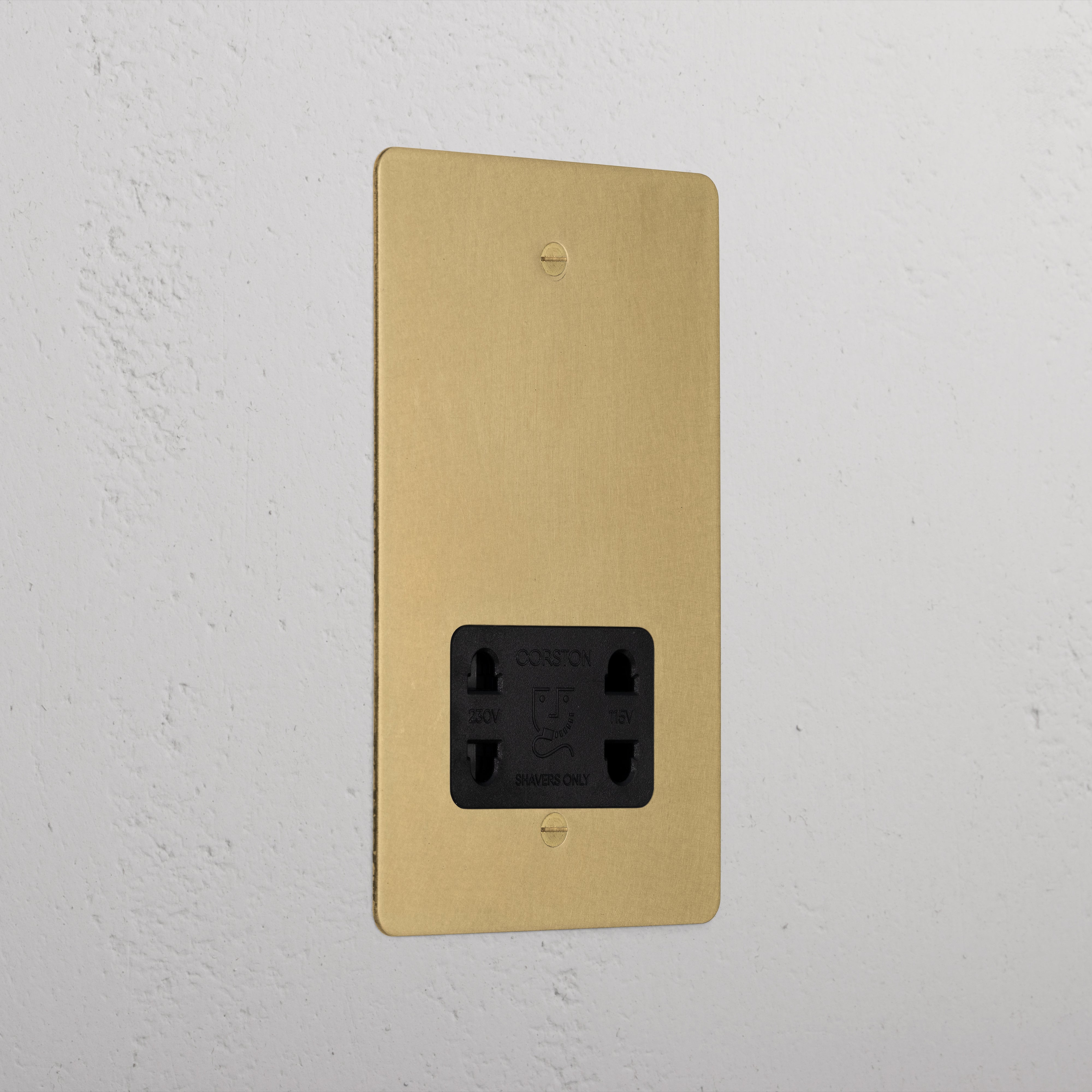 Antique brass shaver socket with black insert on grey wall. 